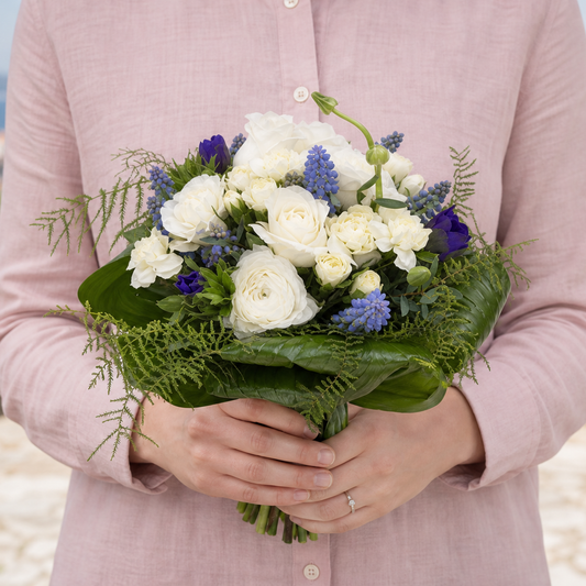 Person holding the BEACH bouquet outdoors, torso only without face
