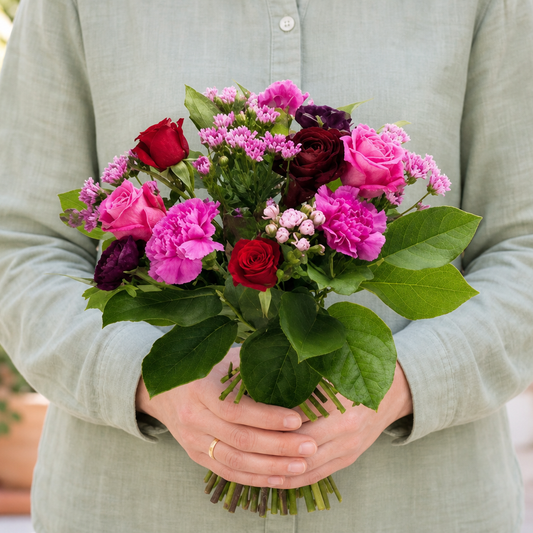Person holding the BEAUTIFUL bouquet outdoors, torso only without face