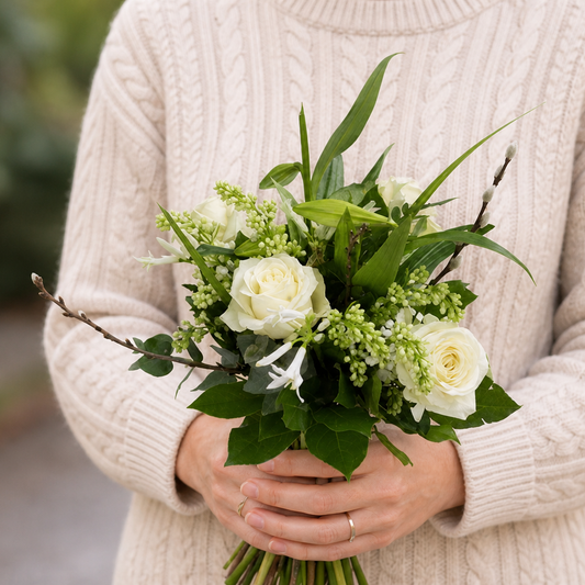 Person holding the ENJOY bouquet outdoors, torso only without face