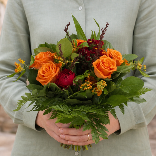 Person holding the EXOTIC bouquet outdoors, torso only without face