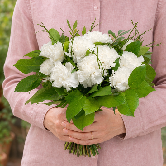 Person holding the FAVORITES bouquet outdoors, torso only without face