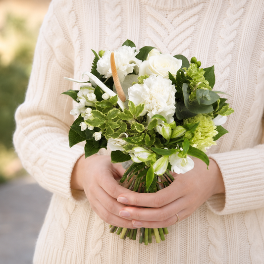 Person holding the NICE bouquet outdoors, torso only without face
