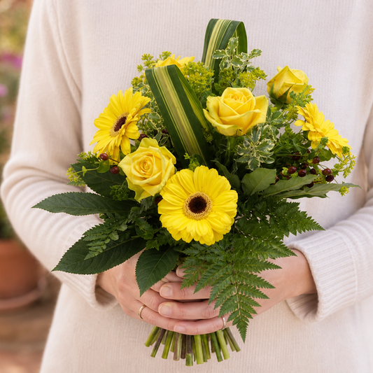 Person holding the TOPAZ yellow bouquet outdoors, torso only without face