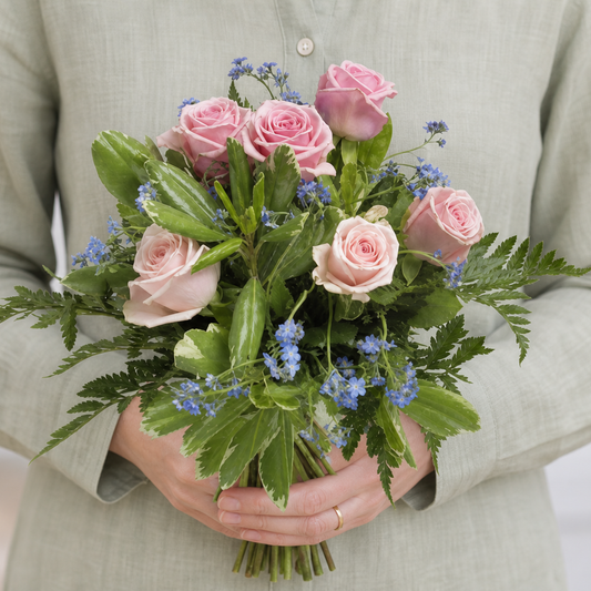 Person holding the YOURS bouquet outdoors, torso only without face